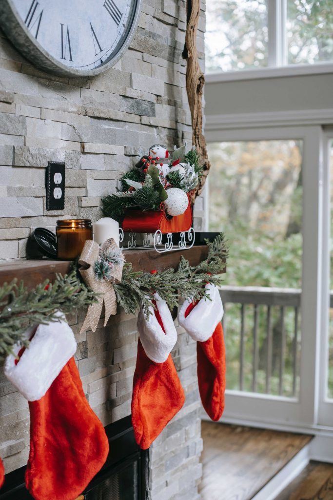 3 stockings hanging on a stone mantel with garland