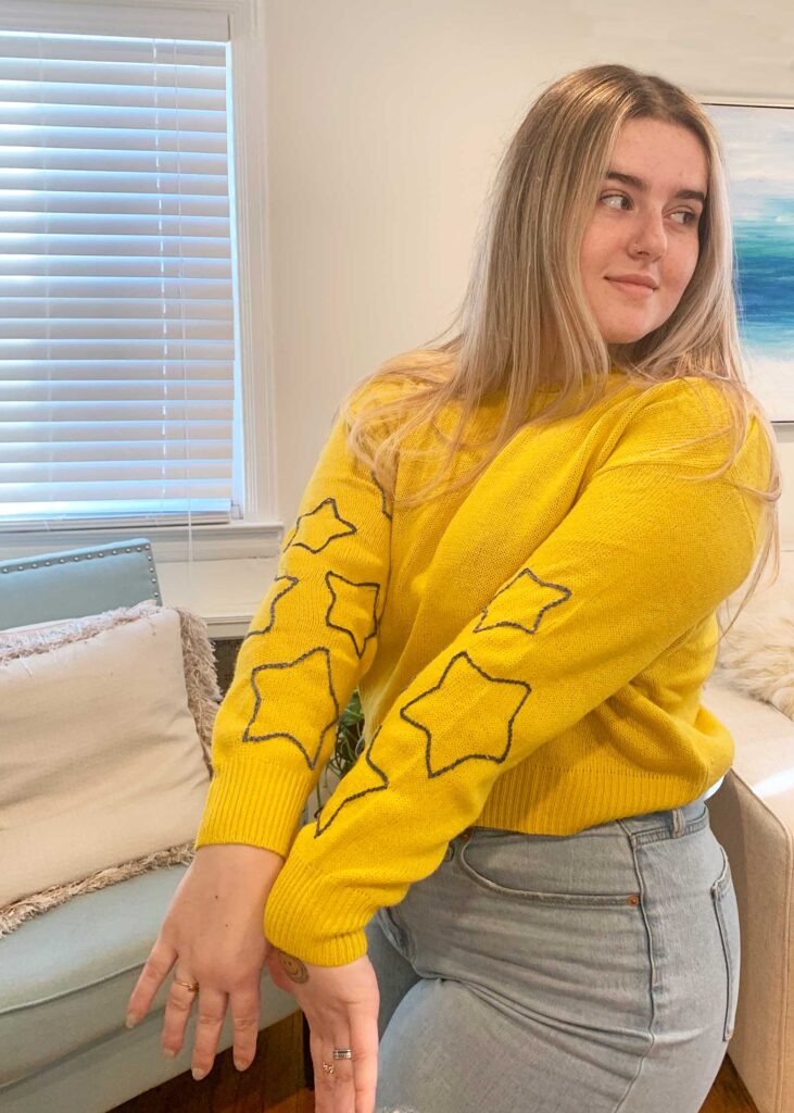 Girl in a yellow sweater with embroidered stars on sleeve