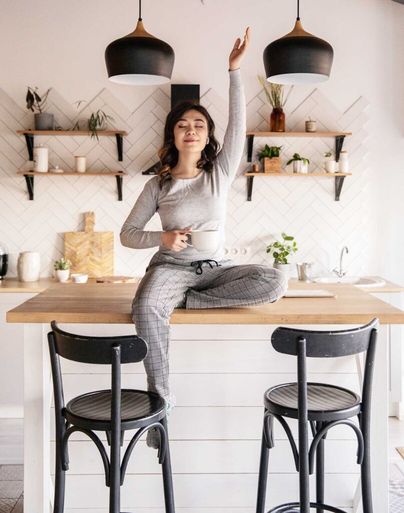 women sitting on kitchen counter in pajamas holding a cup of coffee