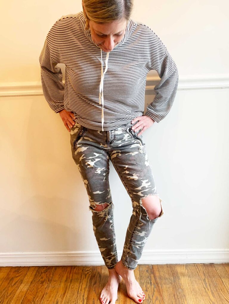 woman looking down at her ripped camo pants knees