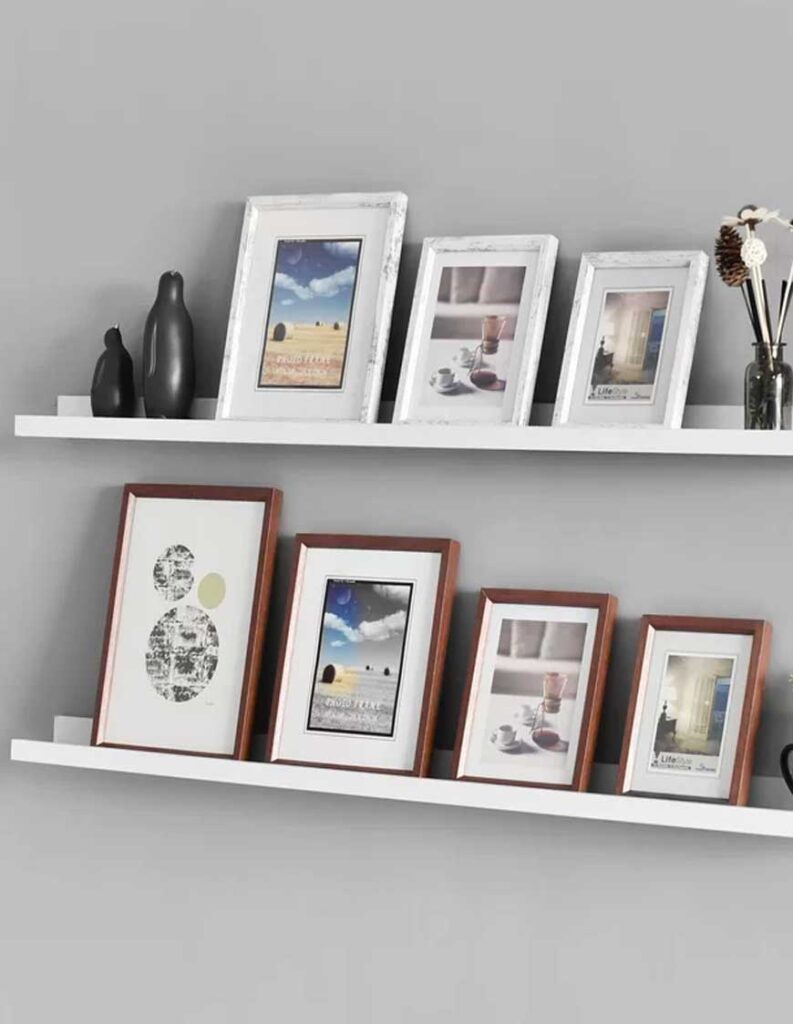 white floating shelves with two rows of picture frames and additional trinkets.