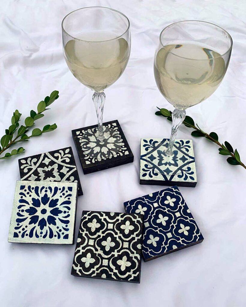 painted wood coasters displayed with two wine glasses.