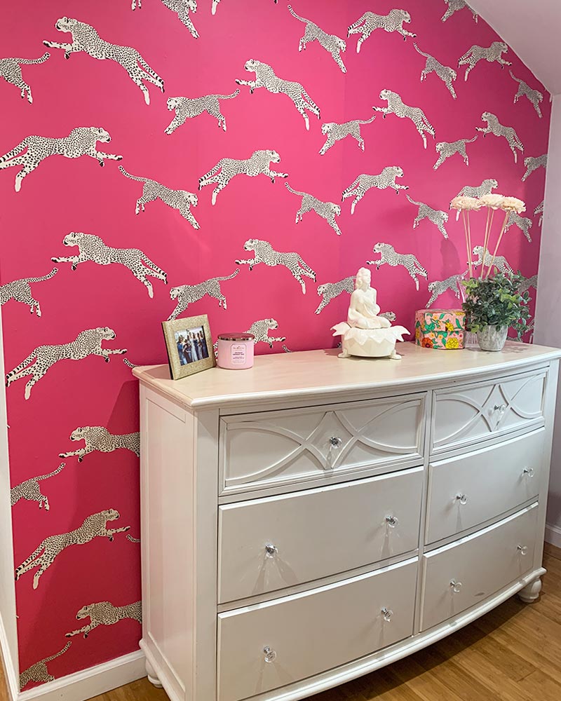 bedroom wallpaper feature wall with white dresser and hot pink wallpaper with cheetahs
